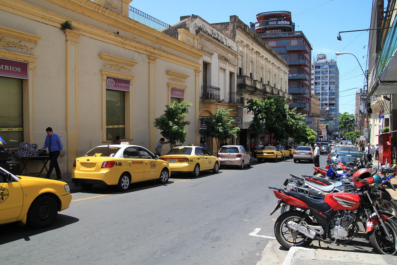 Straße in Asunción mit gelben Taxis, Motorrädern und Wechselstuben
