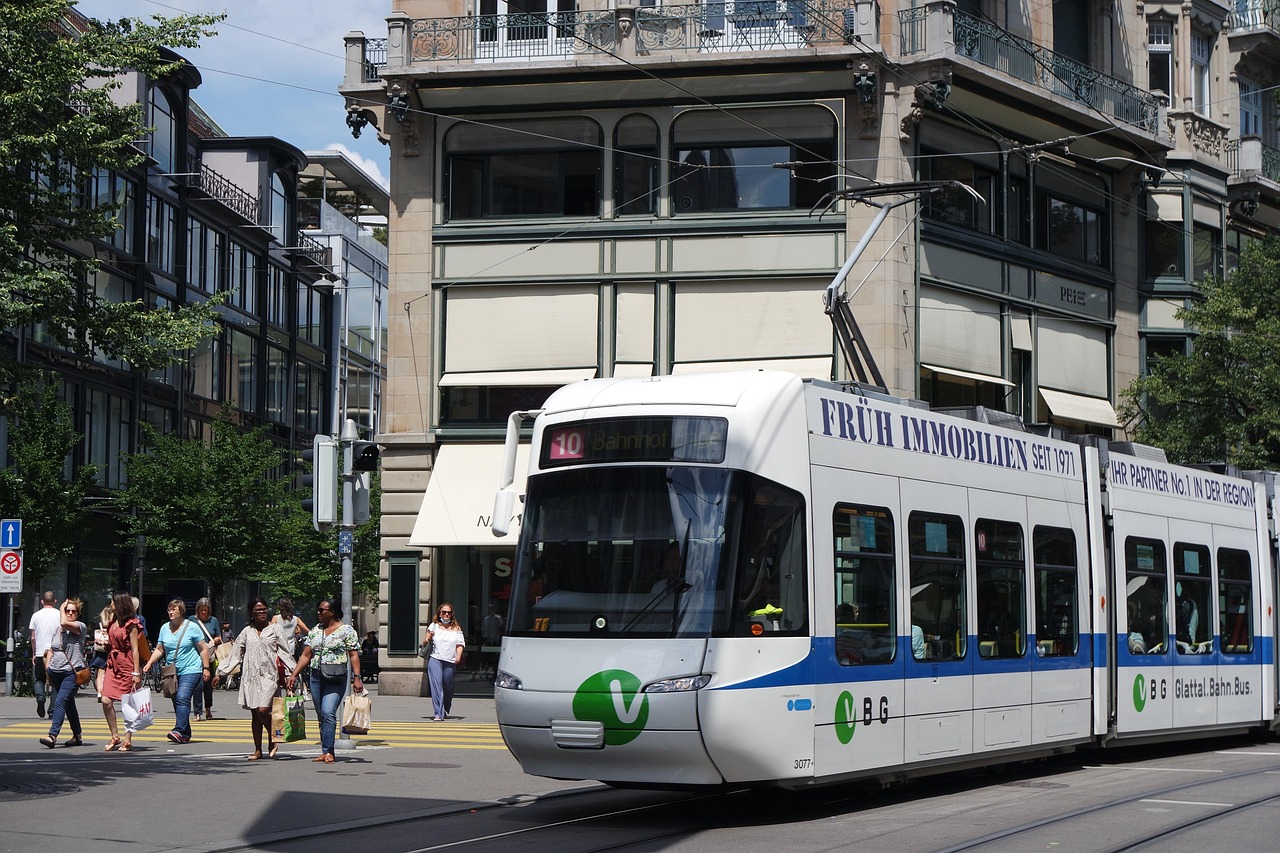 Straßenbahn an einer Haltestelle an der Zürcher Bahnhofstrasse, Menschen auf dem Gehweg